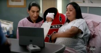 A Native couple hold a baby in a Tulalip cradleboard